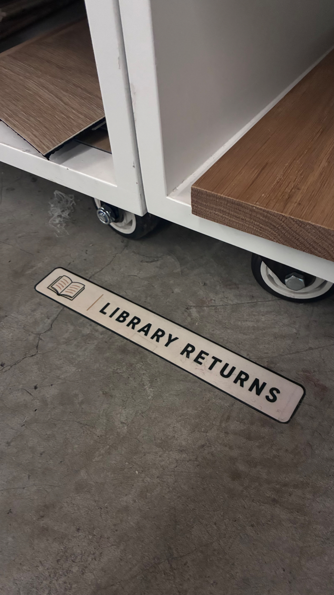Library Returns floor marker on the concrete floor beside a rolling materials cart